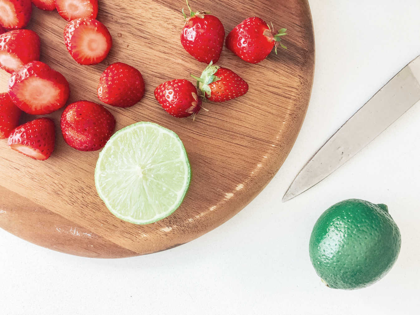 using 4 ingredients, fresh strawberries, lime, ice and rum to make a daiquiri